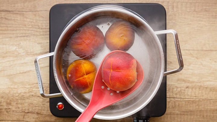 قرار دادن هلو در آب جوش برای پوست کندن آن قرار دادن هلو در آب جوش برای پوست کندن آن