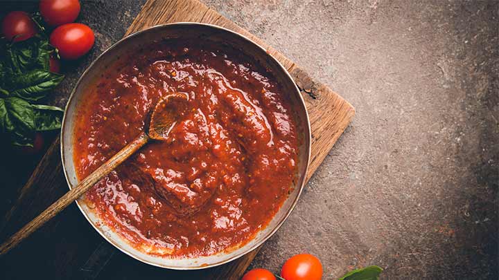 قرار دادن آبکش روی در قابلمه برای جلوگیری از پاشیدن رب گوجه هنگام پخت