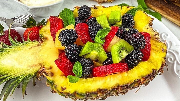 میوهها را خرد کنید و درون آناناس بریزید میوهها را خرد کنید و درون آناناس بریزید